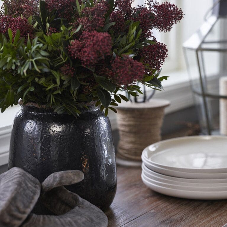 Dekorativ svart vase med sesongens blomster skaper en varm velkomst på skjenken – perfekt kombinert med nøytralt servise og naturlige materialer.